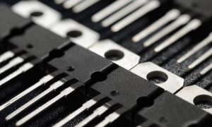 An extreme close up of a set of black and silver power transistors all lined up in rows and columns.