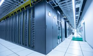 The corner of two intersecting rows of floor-to-ceiling server racks with a professional in a white coat monitoring them.